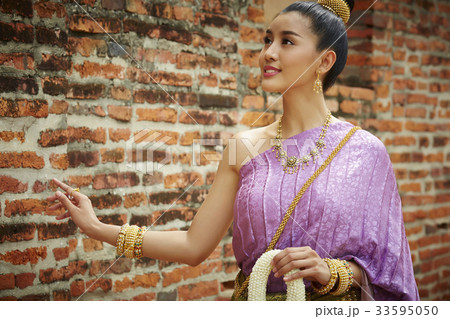 happy woman is walking along brick wall while holding flower garland happy woman is walking along brick wall while holding flower garland 33595050