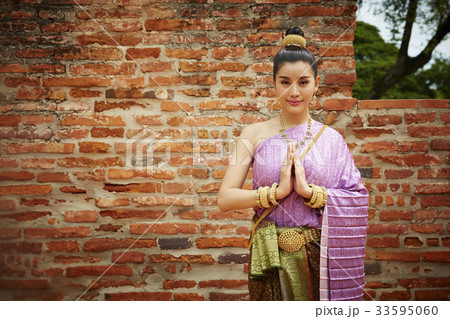 a portrait of smiling thai woman in traditional costume with hands together outdoors 33595060
