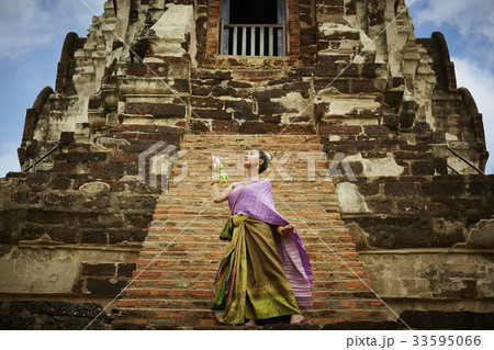 a thai woman in traditional costume is performing in front of temple 33595066