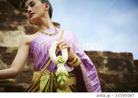 thai woman is standing and holding ornament outdoors thai woman is standing and holding ornament outdoors 33595087