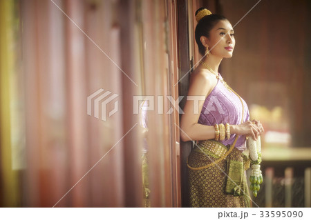 thai woman is leaning against wall and looking at something 33595090