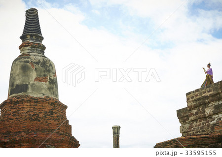A Thai woman is standing on a top opposite a tower of a temple 33595155