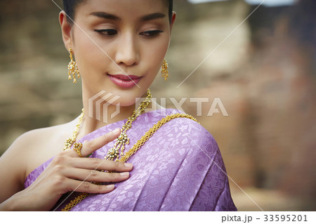 a portrait of a Thai girl touching her traditional costume and looking 33595201