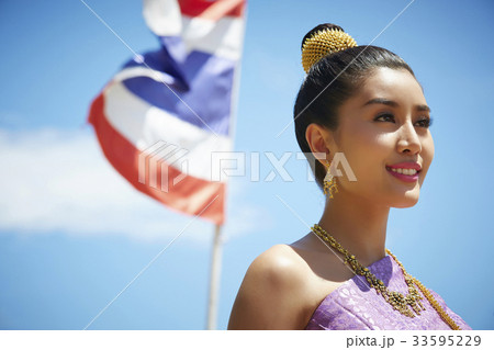 A Thai young woman is smiling happily beside the flag. A Thai young woman is smiling happily beside the flag. 33595229