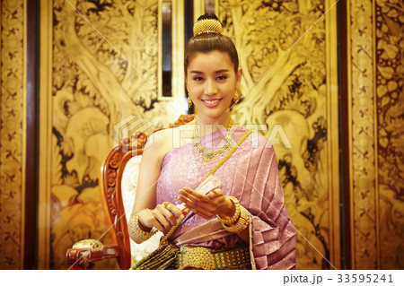 A photo of a beautiful Thai woman sitting and smiling confidently indoor. 33595241