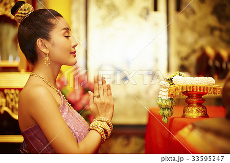 A Thai young woman is praying in front of the Thai ornament. A Thai young woman is praying in front of the Thai ornament. 33595247