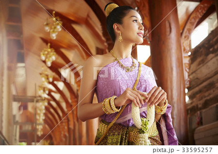 A beautiful woman walks through the corridor while staring at something. 33595257
