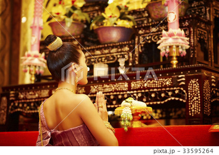 A portrait of beautiful Thai woman genuflecting and praying in front of the altar. 33595264