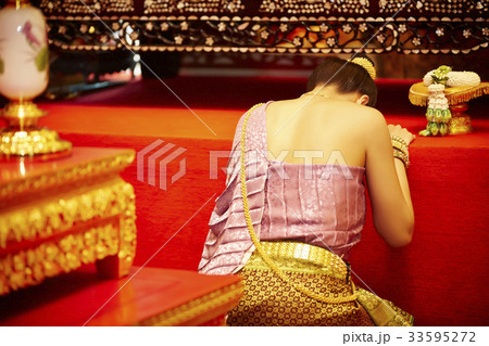 A Thai woman is genuflecting while her face down on the table. 33595272