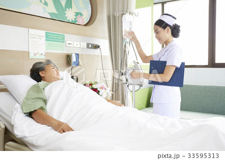The nurse is checking the saline bottle and looking at the patient. The nurse is checking the saline bottle and looking at the patient. 33595313
