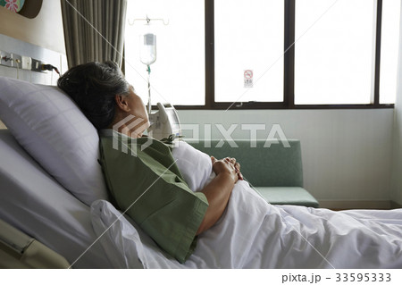 The elderly patient is lying on the bed and looking outside The elderly patient is lying on the bed and looking outside 33595333