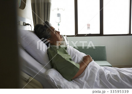 The elderly patient is lying on the bed in the hospital 33595339