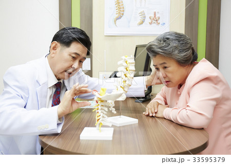 a doctor is explaining to the woman about structure of the spine a doctor is explaining to the woman about structure of the spine 33595379