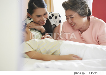 mother and grandmother are smiling and taking care of little girl 33595398