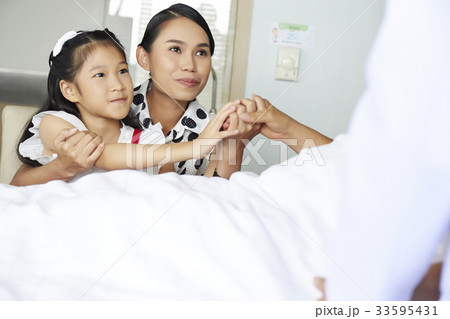 two female people are visiting and holding hand their relative in hospital 33595431