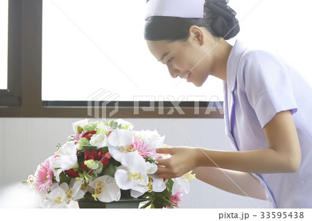young female nurse is arranging flower and smiling in hospital 33595438