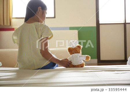 little girl is sitting on bed and looking at teddy bear little girl is sitting on bed and looking at teddy bear 33595444
