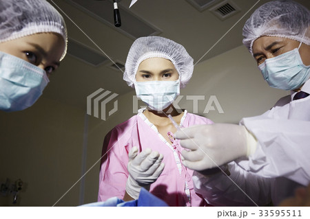 A photo of doctor and nurses standing in surgeon room 33595511