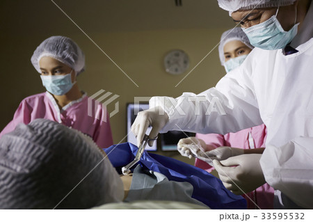 The picture of a doctor and nurses doing a surgery for a patient 33595532