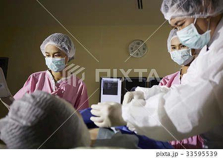 The picture of a practioner and two nurses doing a surgery 33595539