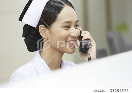 A photo of Asian young nurse talking on phone and smiling in the hospital. A photo of Asian young nurse talking on phone and smiling in the hospital. 33595575