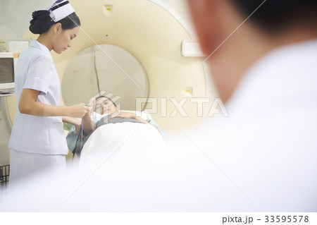 The doctor is looking while the young nurse helping her patient. 33595578