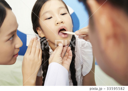 the doctor is examining the mouth of the kid patient the doctor is examining the mouth of the kid patient 33595582