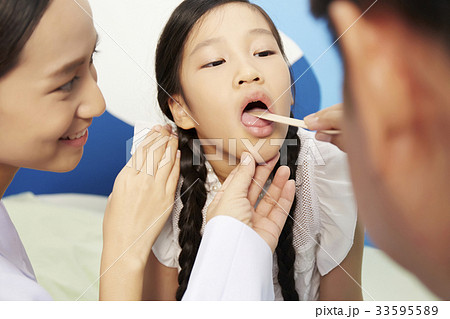 a picture of a doctor checking the teeth of a child 33595589