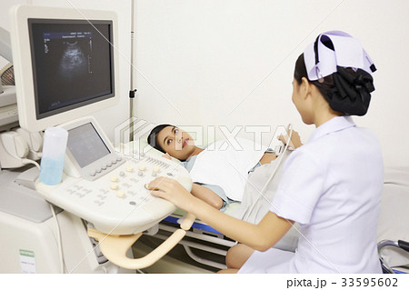 a photo of a nurse checking by scanning her patient in the room 33595602