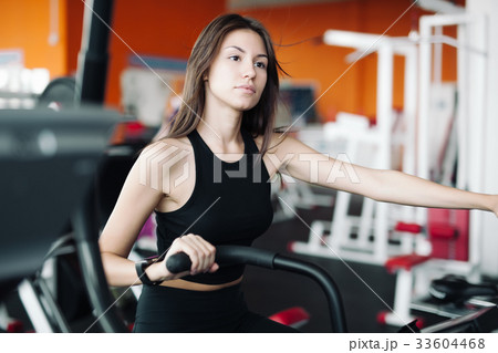 Young girl engaged stationary bike in fitness club Young girl engaged stationary bike in fitness club 33604468