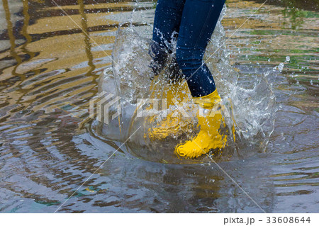 Girl with rain boots jumps into a puddle 33608644