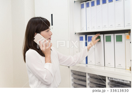 電話しながらファイルを出す女子社員 33613630
