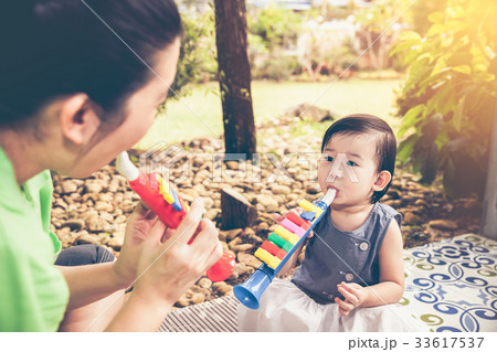 Asian mother playing trumpet pipe with daughter. Asian mother playing trumpet pipe with daughter. 33617537