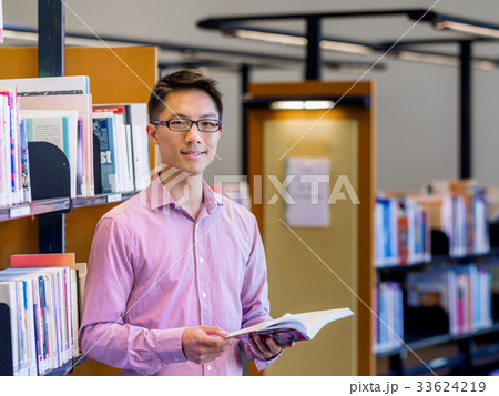 Happy male student holding books at the library 33624219