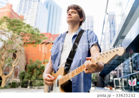 Young musician with guitar in city 33625232
