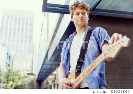 Young musician with guitar in city Young musician with guitar in city 33625349