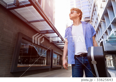 Young musician with guitar in city Young musician with guitar in city 33625643