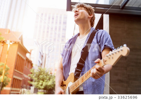Young musician with guitar in city Young musician with guitar in city 33625696