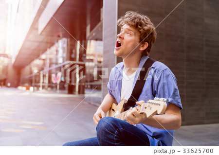 Young musician with guitar in city Young musician with guitar in city 33625700