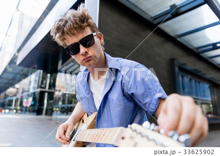 Young musician with guitar in city Young musician with guitar in city 33625902
