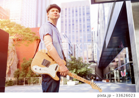 Young musician with guitar in city Young musician with guitar in city 33626023
