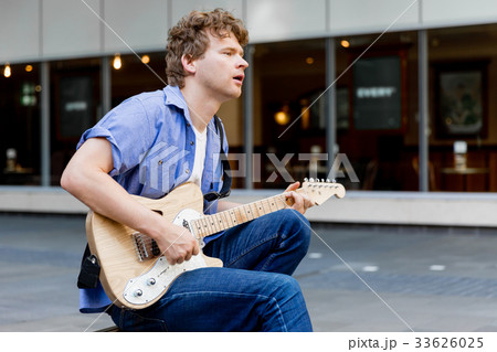 Young musician with guitar in city Young musician with guitar in city 33626025