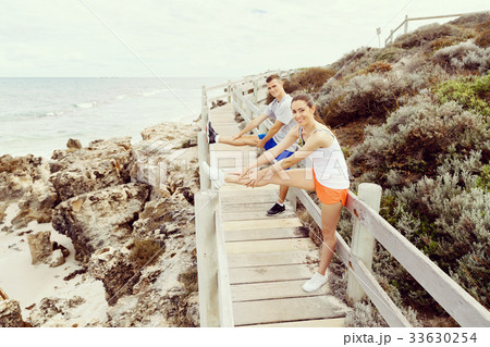 Runners. Young couple exercising and stertching on beach 33630254