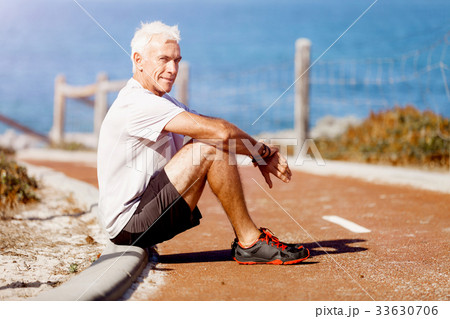 Man in sports wear sitting at the beach 33630706