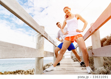 Runners. Young couple exercising and stertching on beach 33631091