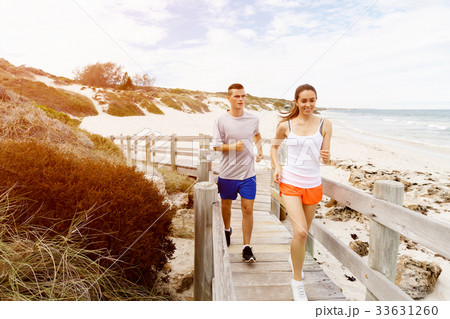 Runners. Young couple running on beach 33631260