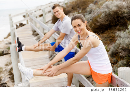 Runners. Young couple exercising and stertching on beach 33631262