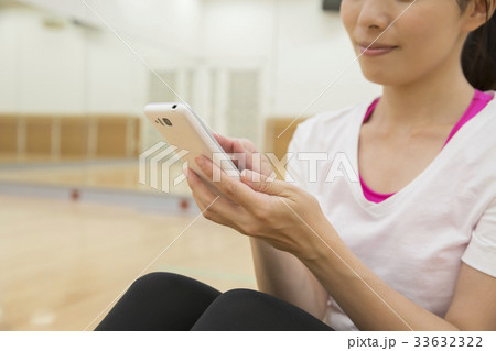 スポーツジムのスタジオでスマホをチェックする女性 スポーツジムのスタジオでスマホをチェックする女性 33632322