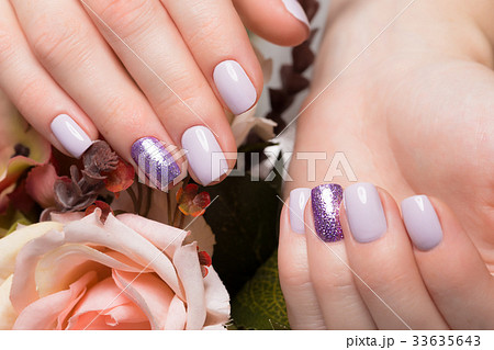 Purple neat manicure on female hands on flowers 33635643