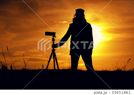 Silhouette of Female photographer against sunset Silhouette of Female photographer against sunset 33651861